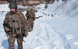 Soldaten in camouflagekleding lopen door de sneeuw.