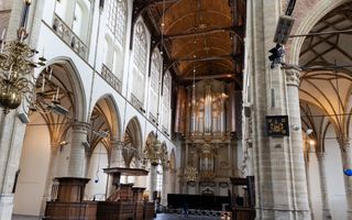 Interieur van de kerk, met hoge pilaren en links de houten kansel. Voorin het grote orgel. 