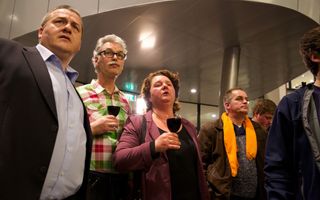 Echtpaar met glas wijn in de hand, kijkt naar de uitslag van de verkiezingen.