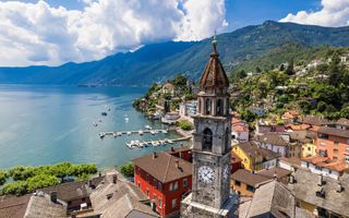 Zicht op een stad in Zwitserland, aan een groot meer. Op de voorgrond is de torenspits van een oude kerk te zien.