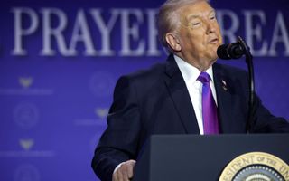 De Amerikaanse president Donald Trump, in donkerblauw pak met paarse stropdas.