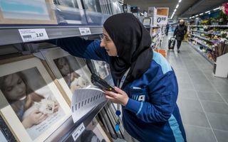 Een medewerker in een filiaal van winkelketen Action controleert de voorraden. Op de achtergrond loopt een klant door het gangpad. 