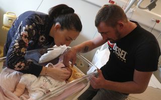 Een man en een vrouw buigen over een baby. 