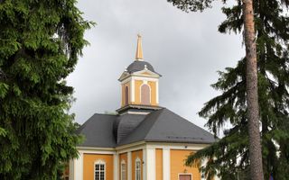 Kerk in de keuren geel en wit op een grasveld met bomen