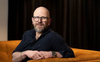 Portret van een kale man met baardje en een donkere blouse.