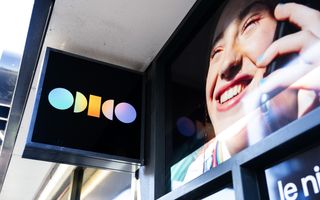 Een uithangbord met het logo van Odido hangt aan de gevel van een winkel.