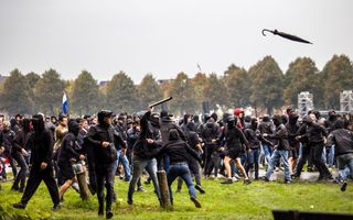Mannen in donkere kleding rennen over het gras en gooien spullen.