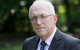 Portretfoto van oudere man, brildragend, grijs colbert.