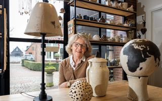 Vrouw achter tafel met voor haar verschillende zelfgemaakte keramieken voorwerpen