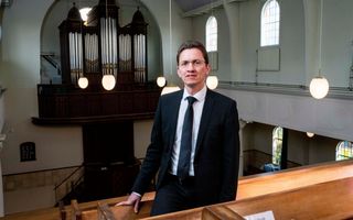 Dominee Van der Staaij, een man met zwart haar, bril op, in een kerk