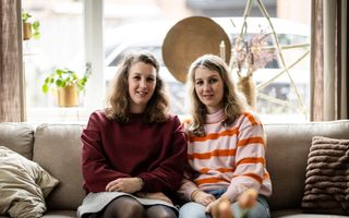 De tweelingzussen Nathalie en Kimberley zitten samen op een bank. Nathalie draagt het haar uit haar gezicht, Kimberley heeft een scheiding.