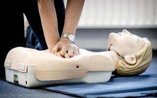 Twee handen duwen op de borst van een witte pop.