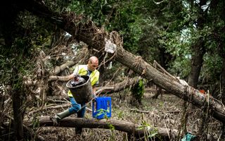 Een vrijwilliger van Natuurmonumenten ruimt afval op in de natuur. 