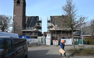Een pakketbezorger loopt door de straat bij de voormalige Julianakerk in Rotterdam. Naast de kerktoren verrijzen woningen.