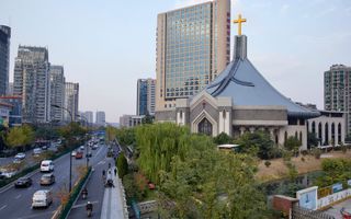 Een grote, grijze kerk middenin een drukke Chinese stad