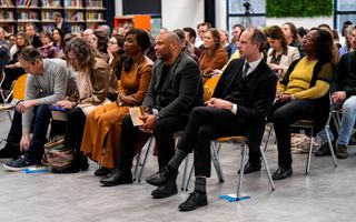 Een zaal met zittende mensen die naar een lezing luisteren.