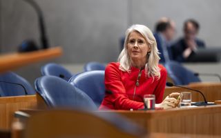 Vrouw in rode outfit, in Tweede Kamer.