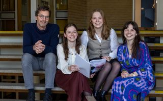 Een docent met drie leerlingen op de trap van hun middelbare school. Eén leerling houdt het profielwerkstuk over de manosfeer vast.