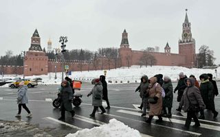 Inwoners van Moskou steken de straat over voor een gebouw van rode steen, omgeven door sneeuw.