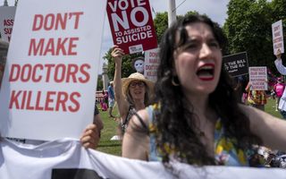 Demonstranten houden borden tegen euthanasie omhoog op een grasveld.