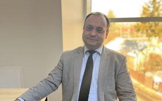 Man in een bruin pak met een stropdas en een hand op de Bijbel.