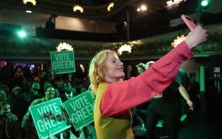 Vrouw neemt selfie in donkere zaal met veel groen.
