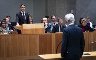 Premier Jetten staat achter katheder in grote vergaderzaal van de Tweede Kamer en PVV’er Geert Wilders achter de interruptiemicrofoon,