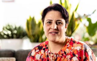 Vrouw van middelbare leeftijd met kort donker haar in een roodachtige blouse.