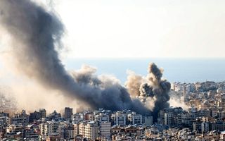 Rookpluimen stijgen op boven een stad aan zee.