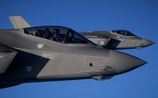 Twee grijze, spitse neuzen van vliegtuigen tegen een strakblauwe hemel.