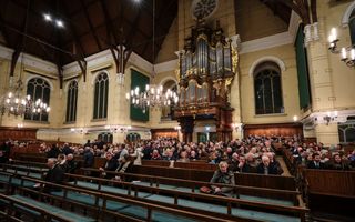 Een grote kerk, die vijf minuten voor aanvang voor een heel deel gevuld is. Tegen de achterwand het rijkversierde orgel.