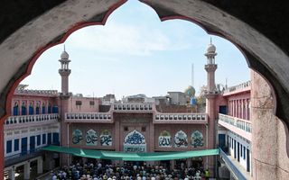 Een grote groep moslims op het plein voor een moskee.