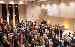 Moderne kerkzaal met veel mensen die staan.