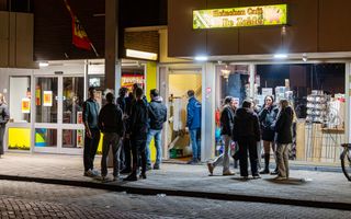 Jongeren staan ‘s avonds voor een verlicht gebouw.