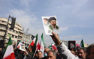 Mensen zwaaien met vlaggen en portretten op een plein in de Iraanse hoofdstad.