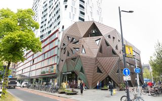 Exterieur van de Pauluskerk, met daarachter een hoog gebouw en op de voorgrond mensen en fietsen.