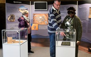 Twee vitrines waar mensen bij staan te kijken. In de vitrines liggen replica’s van oude teksten die met de Bijbel of met de ontwikkeling van het schrift te maken hebben.