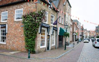 Winkelstraat met auto’s en vlaggetjes.