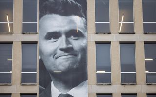 Een grote afbeelding met het gezicht van Charlie Kirk, bevestigd op een gebouw. 