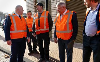 Minister Aartsen maakt een praatje met een bouwvakker tijdens zijn werkbezoek