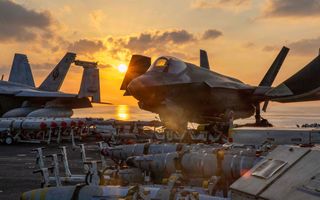 Straaljagers en rekken met bommen staan op dek van schip op zee.
