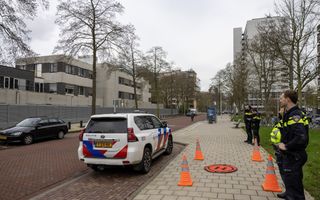 Een politiewagen en enkele agenten op de stoep. Op de achtergrond het schoolgebouw met metalen muur. 