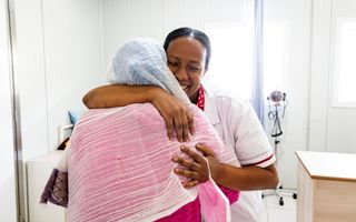 Verpleegkundige krijgt een knuffel van een patiënte.