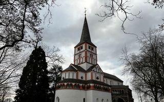 Een oude kerk met witte muren en rode bakstenen, met een toren.