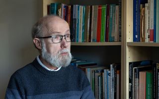 Pieter Lalleman, een man met grijze baard, bril op, blauwe trui aan.