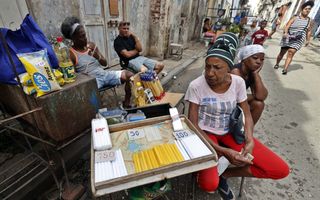 Een vrouw zit naast een tafel waarop kaarsen liggen uitgestald.