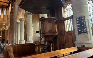 Kerkinterieur van een oude kerk, met een donkergelakte houten kansel.