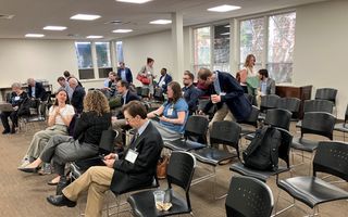 Mensen zitten op stoelen in een zaal.