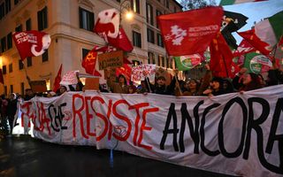 Mensen houden een wit spandoek voor zich terwijl het donker wordt. 