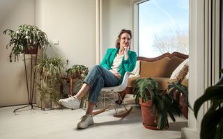 Porcelijn zit op een bank in een kamer met planten.